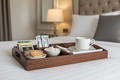 Plateau de courtoisie en bois posé sur un lit d'hôtel avec thé, café et biscuits